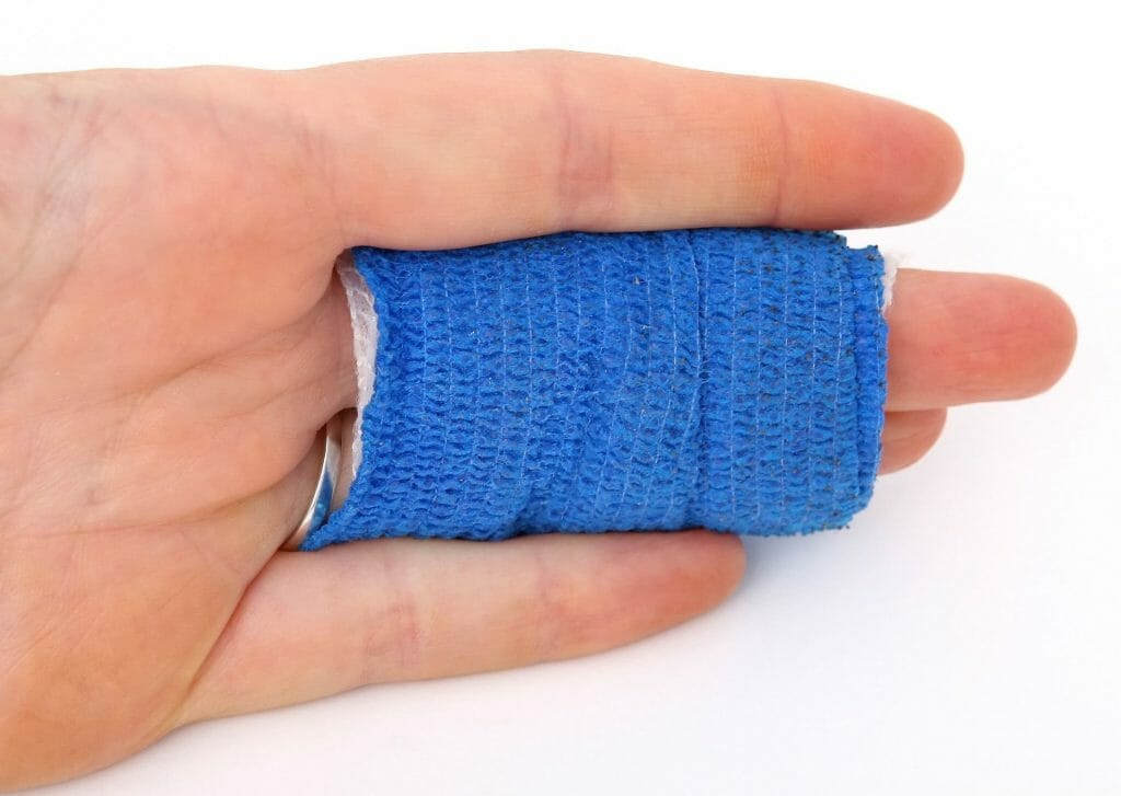 Een hand met blauw zelfhechtend verband om twee vingers